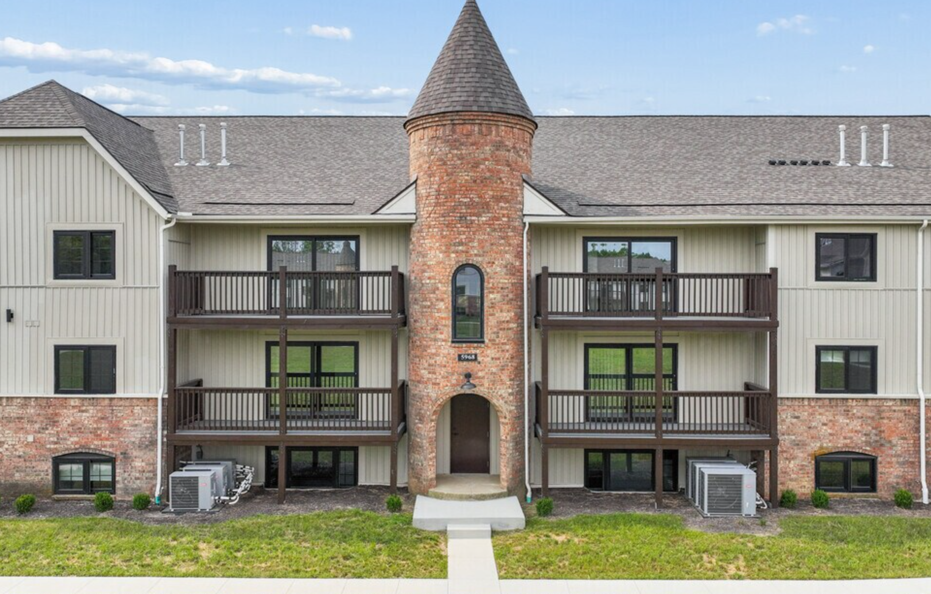 Maison Hills exterior — garden-style apartment building with brick tower and private balconies in Dayton, OH