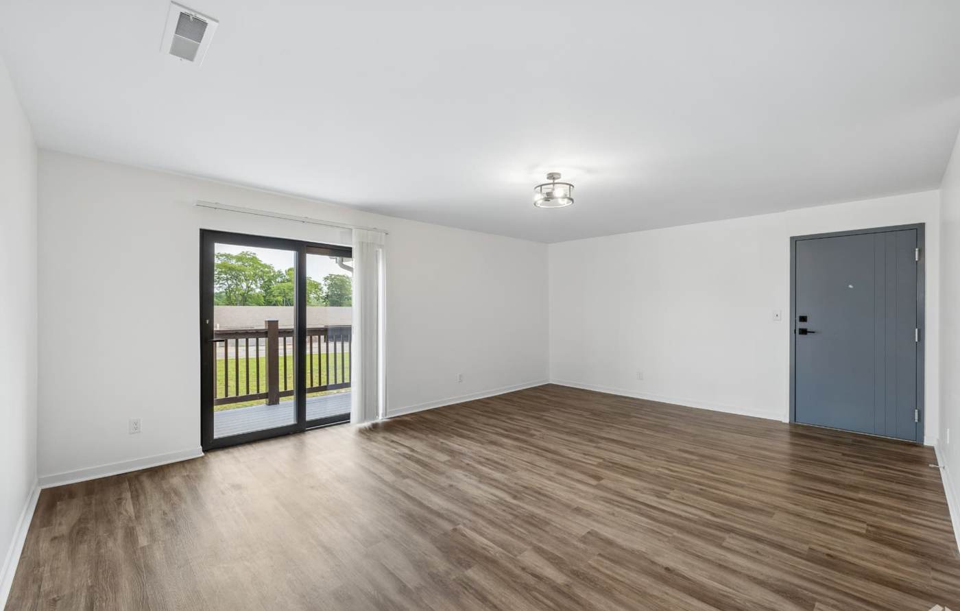 Spacious living room with wood-style flooring and sliding balcony doors